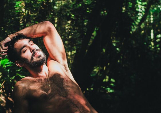photo of a topless man surrounded by plants