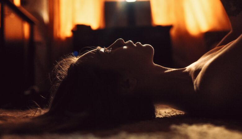 young alluring woman lying on carpet in dark room